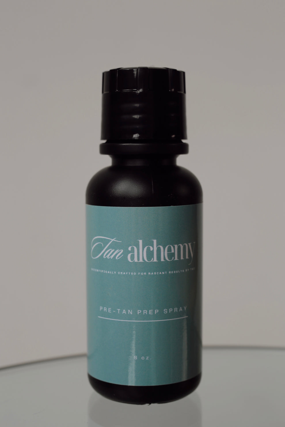 Black bottle with a teal label on a reflective surface