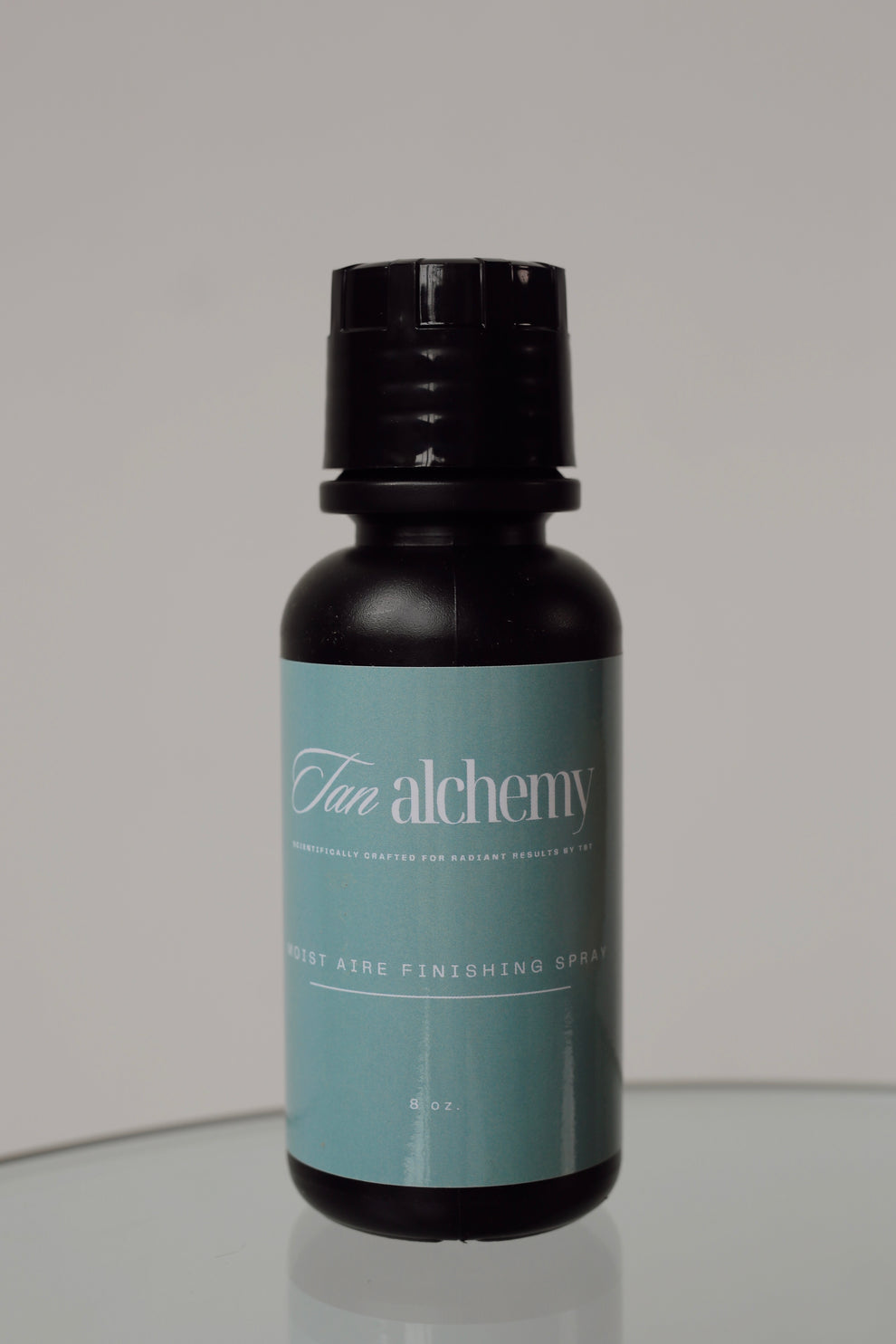 Bottle of 'Fun Alchemy' product on a reflective surface with a gray background