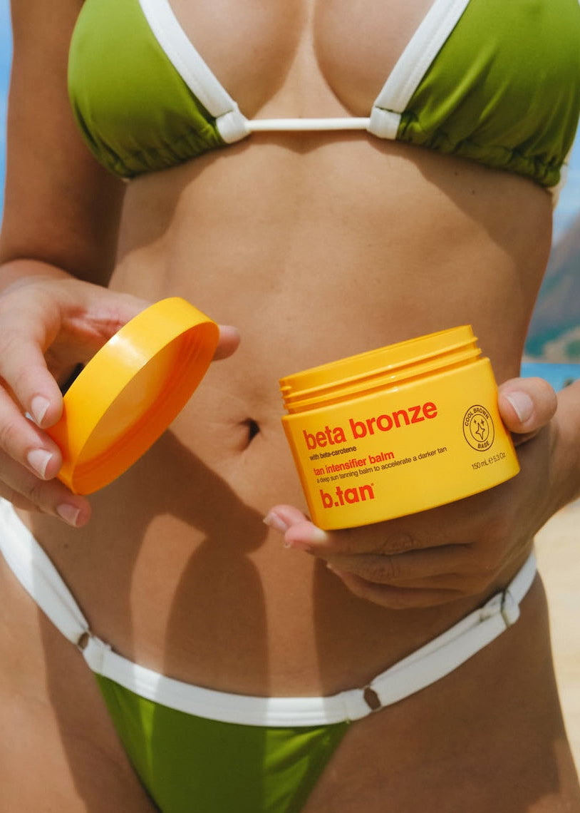 Person holding a jar of 'beta bronze' sunless tanning product with a green bikini.