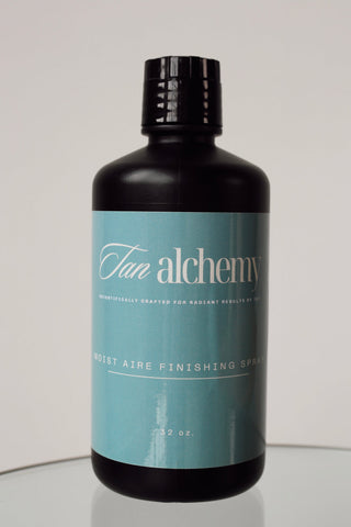 Bottle of 'Tan Alchemy' product on a reflective surface with a neutral background
