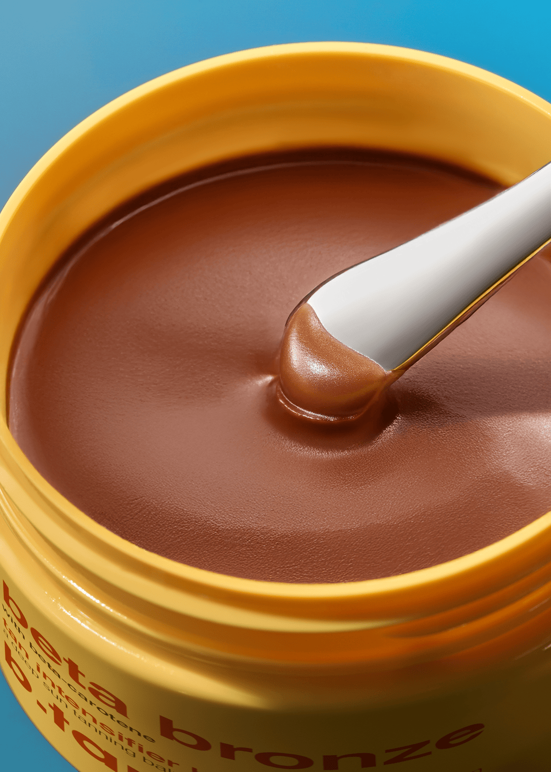Bronze-colored cream with a white applicator on a blue background