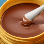 Bronze-colored cream with a white applicator on a blue background