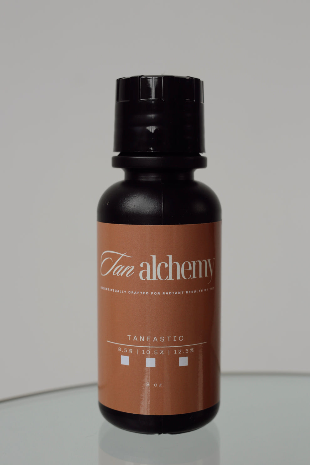 Tan alchemy bottle on a reflective surface with a neutral background