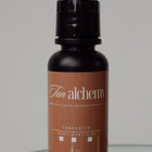 Tan alchemy bottle on a reflective surface with a neutral background
