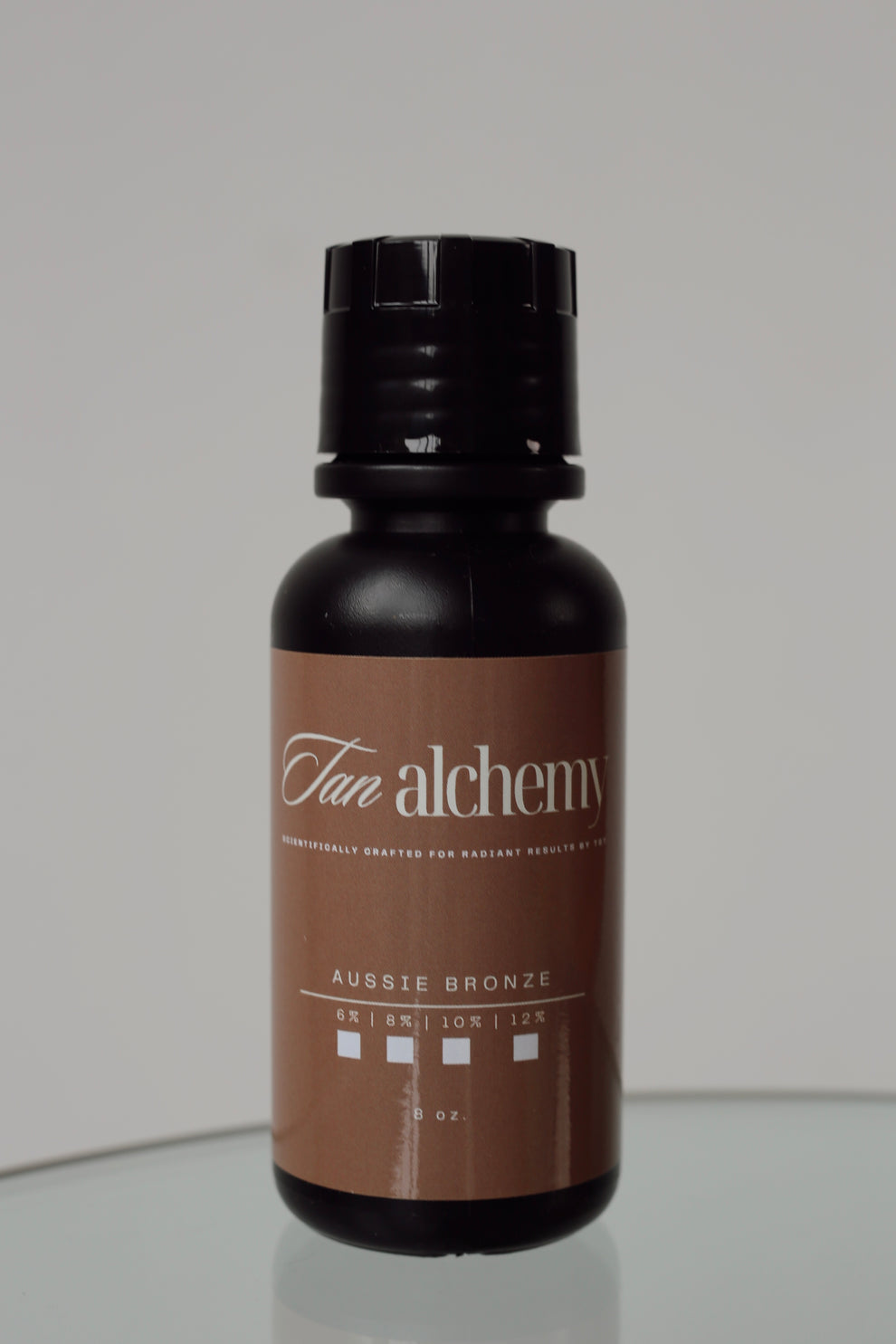 Tan alchemy bottle on a reflective surface with a neutral background