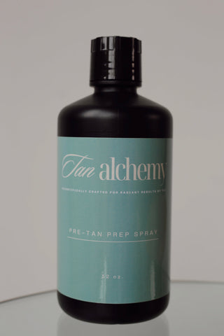 Black bottle with teal label featuring 'Tan alchemy' on a gray background