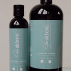 Two bottles of 'Two Alechemy' cream on a reflective surface with a neutral background