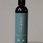 Bottle of 'The Alchemy' barrier cream on a reflective surface with a neutral background