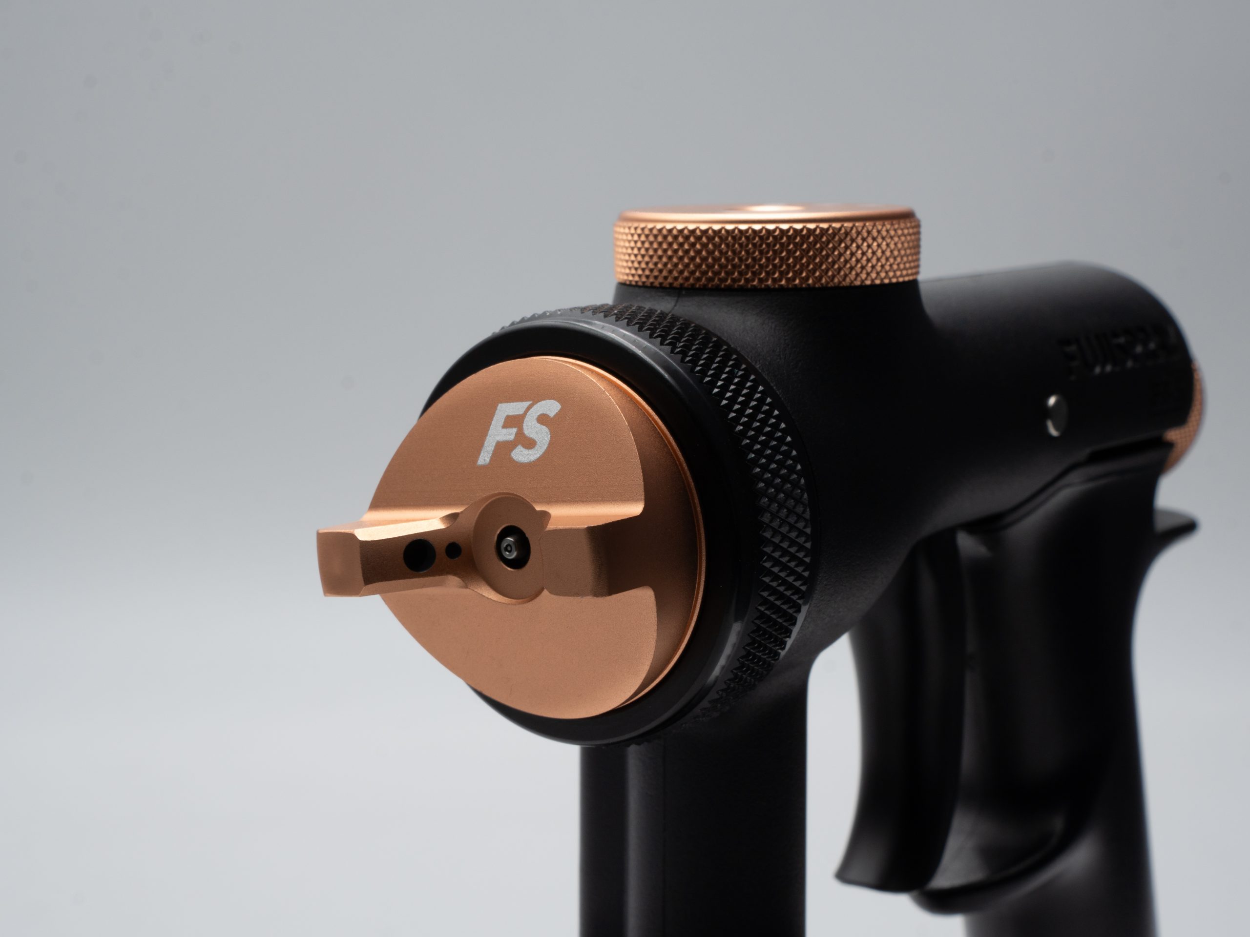 Black and copper spray gun nozzle with 'FS' branding on a gray background