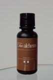 Bottle of 'Tan Alchemy Revive' on a reflective surface with a neutral background