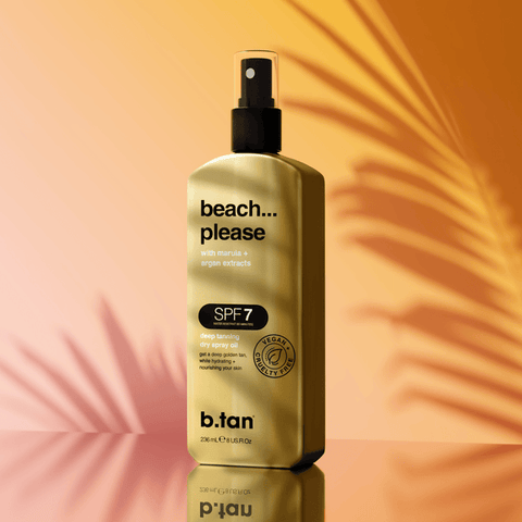 Gold bottle of b.tan 'beach... please' sunscreen spray on a warm gradient background