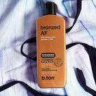 B.tan bronzed AF tan accelerating bronzing lotion bottle on a textured white background