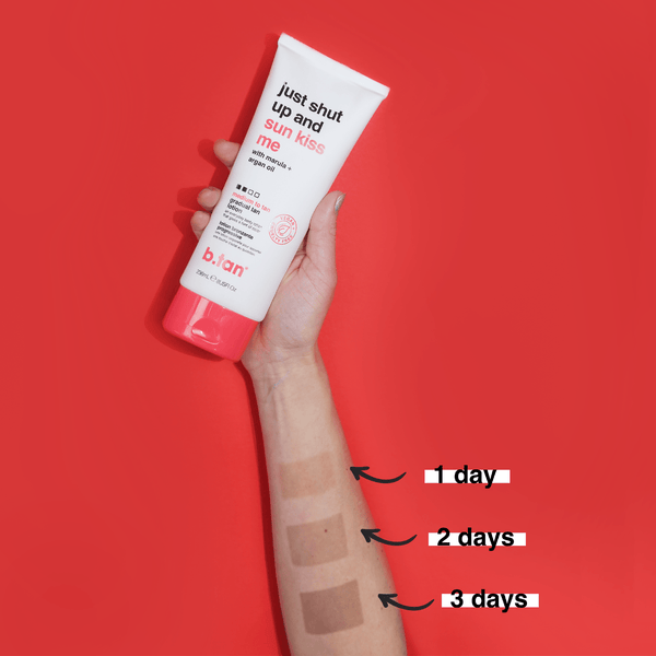 Hand holding a tube of sunscreen with application swatches on a red background
