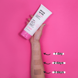 Hand holding a tube of 'plump up the bronze' tanning product with application on arm showing color change over days on a pink background.