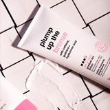 Cosmetic tube labeled 'plump up the bronze' on a tiled surface with visible product.
