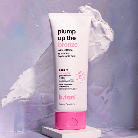 b.tan gradual tan lotion tube with pink cap on a white platform against a colorful abstract background