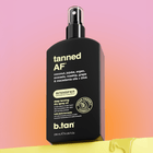 Black spray bottle labeled 'tanned AF' on a gradient background