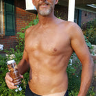 Man outdoors holding Rapid Tan Spray Tan Solution , wearing black underwear