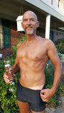 Man outdoors holding Rapid Tan Spray Tan Solution , wearing black underwear