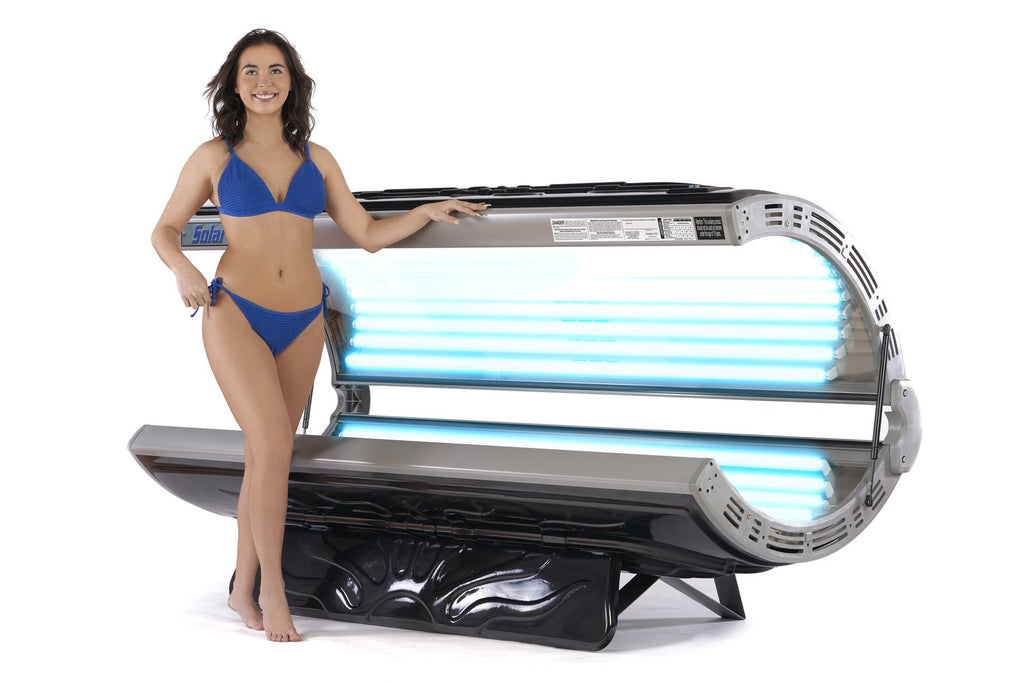 Woman in blue bikini stands by a Solar Storm 32S Residential Tanning Bed - 110V.